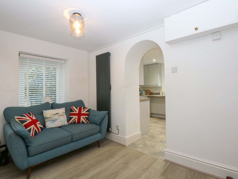A living room with a sofa and kitchen access at 4 Brynteg Terrace in Menai Bridge
