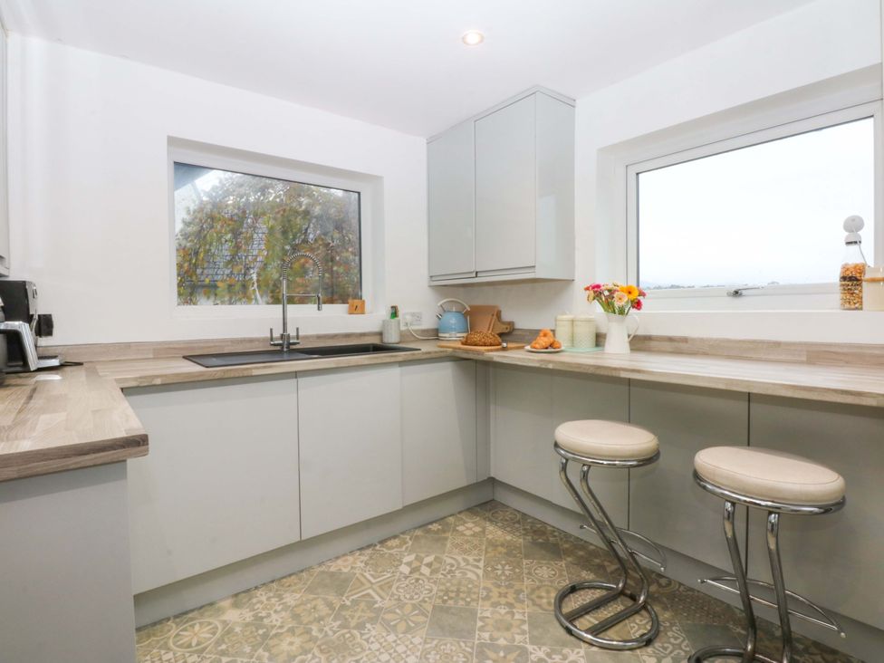 A kitchen with a sink and stools at 4 Brynteg Terrace in Menai Bridge