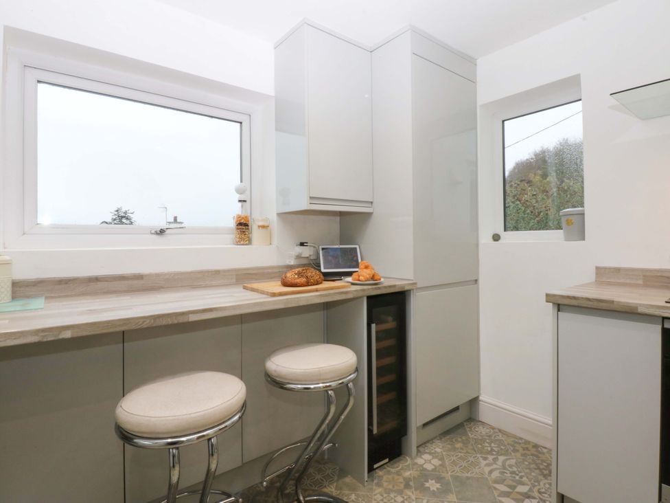 A kitchen with countertop, barstools, and a tablet at 4 Brynteg Terrace in Menai Bridge