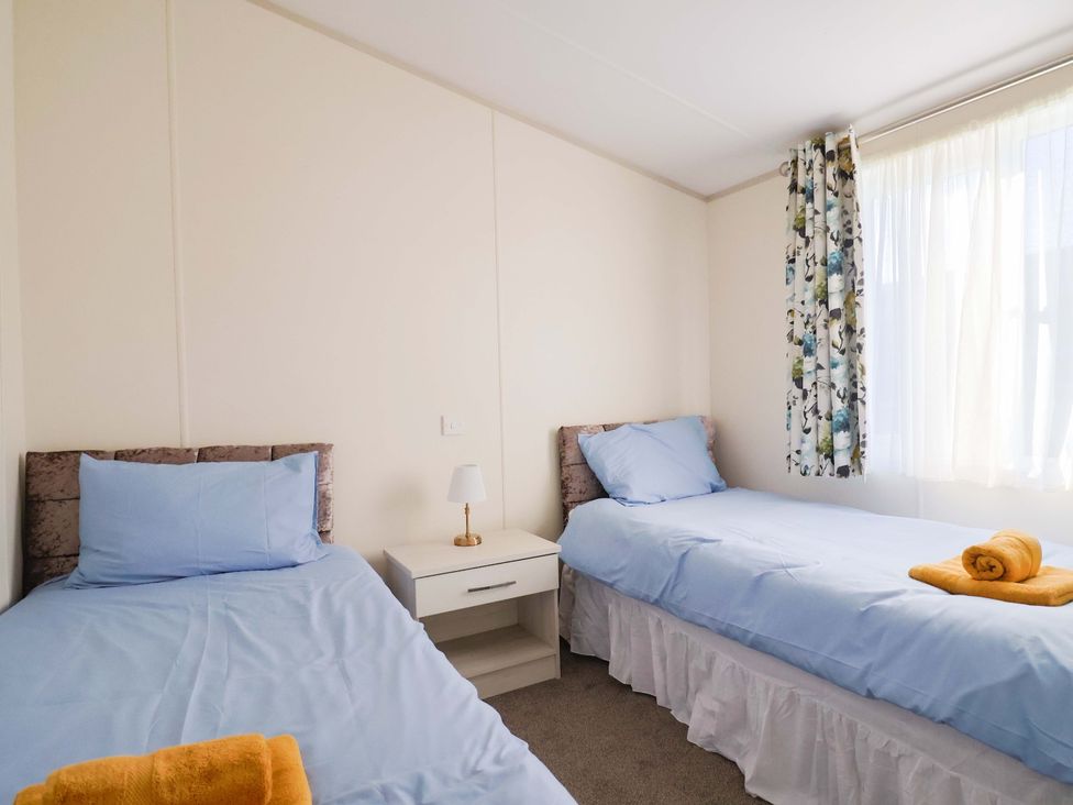 A bedroom with two beds and a lamp at 91 Swanage Coastal Park in Swanage