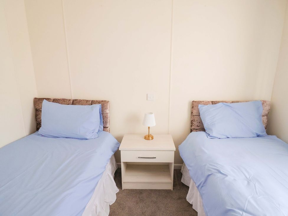 A bedroom with two single beds and a nightstand at 91 Swanage Coastal Park in Swanage