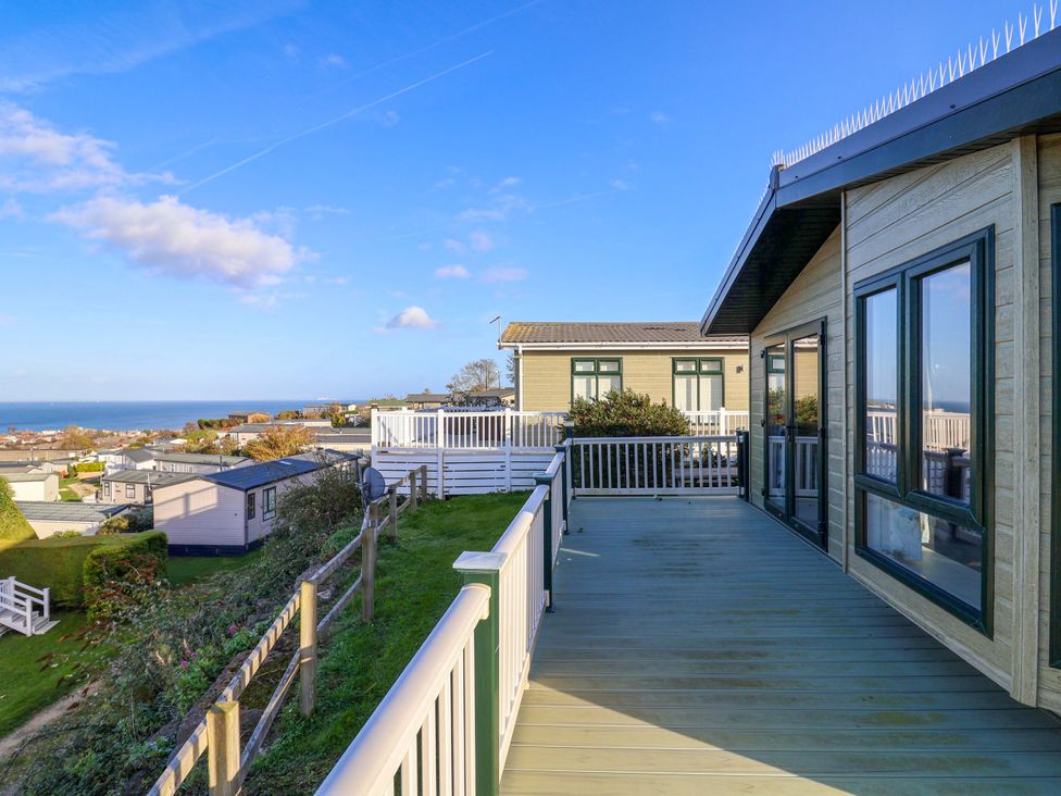 An outdoor deck with a view of houses and ocean at 91 Swanage Coastal Park in Swanage