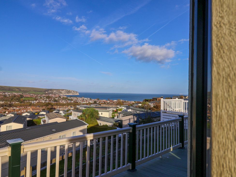 A view of the ocean and hills from a balcony at 91 Swanage Coastal Park in Swanage