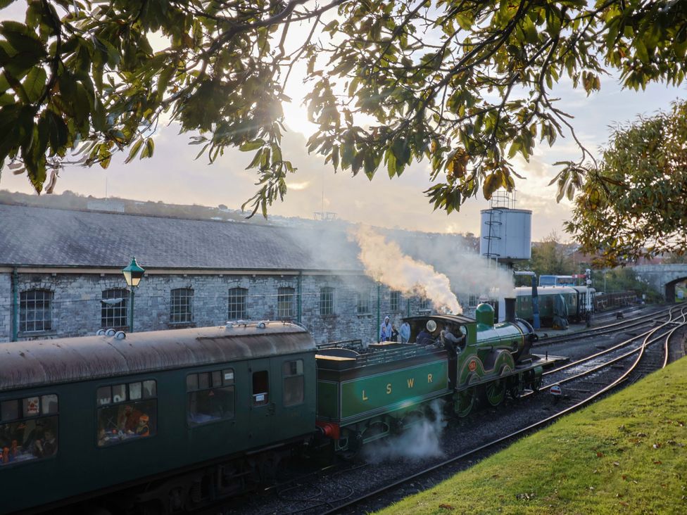 A steam locomotive and train car at a railway station near a brick building at 91 Swanage Coastal Park in Swanage