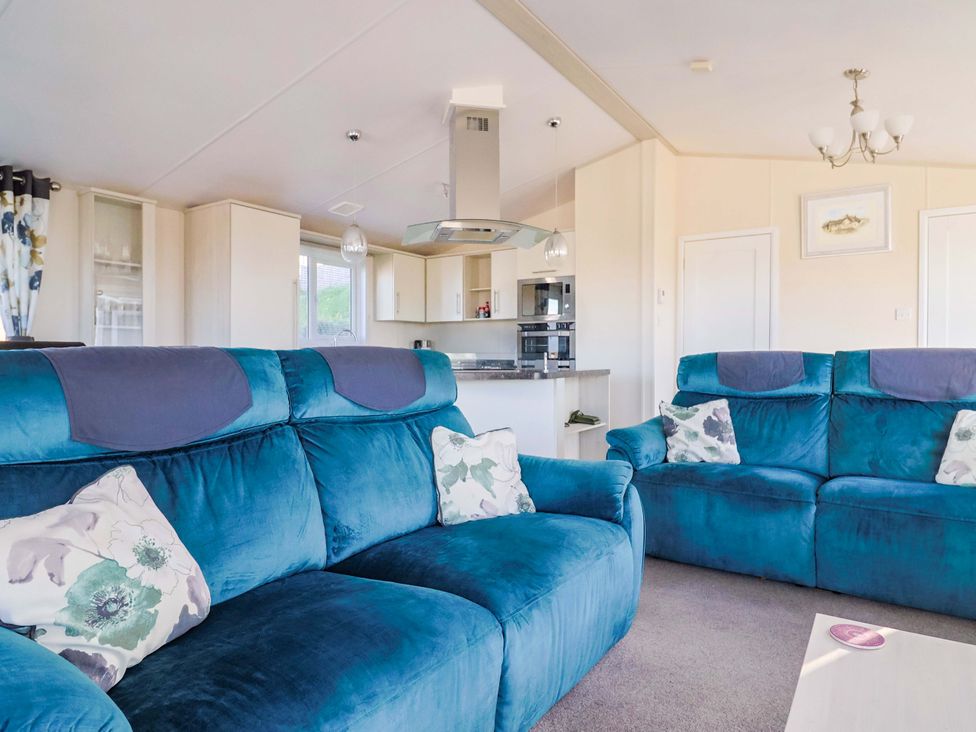 A living room with sofas and a kitchen area at 91 Swanage Coastal Park in Swanage