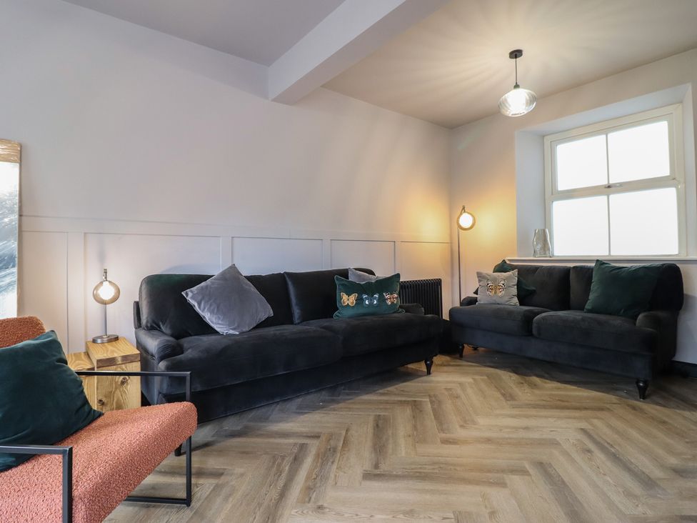 A living room with sofas and a lamp at Green Bank in Betws-Y-Coed