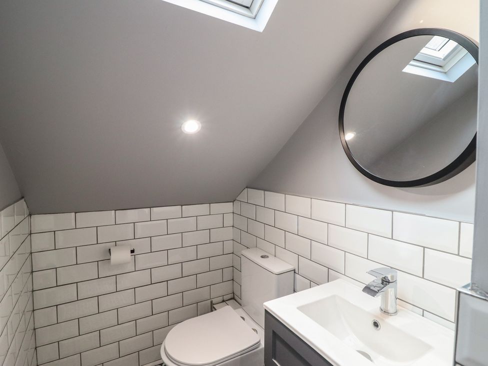 A bathroom with toilet, sink and mirror at Green Bank in Betws-Y-Coed