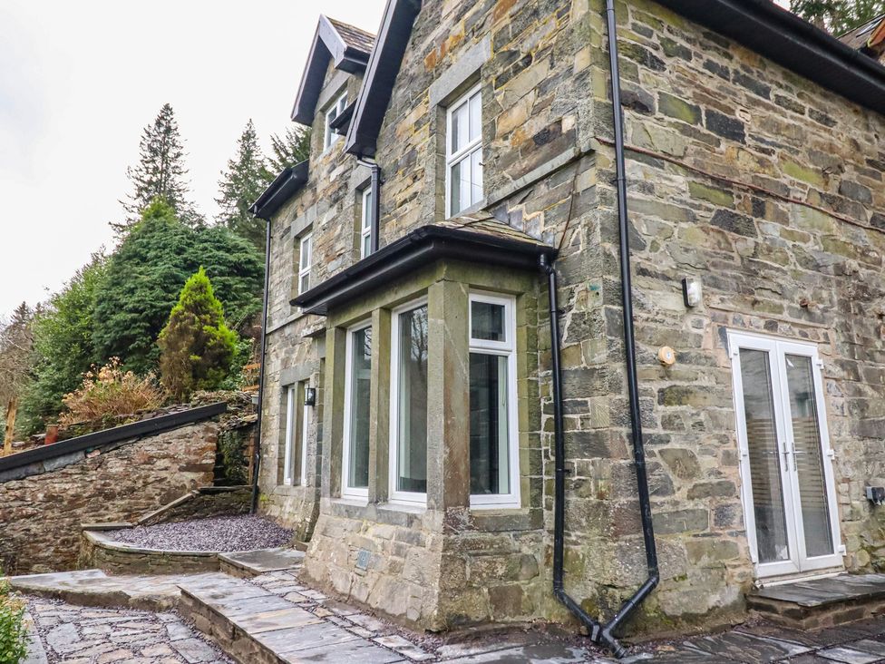 An exterior view of a stone house with windows and a pathway at Green Bank in Betws-Y-Coed