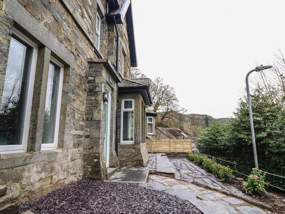 An exterior view of a stone house with a slate path and garden at Green Bank in Betws-Y-Coed