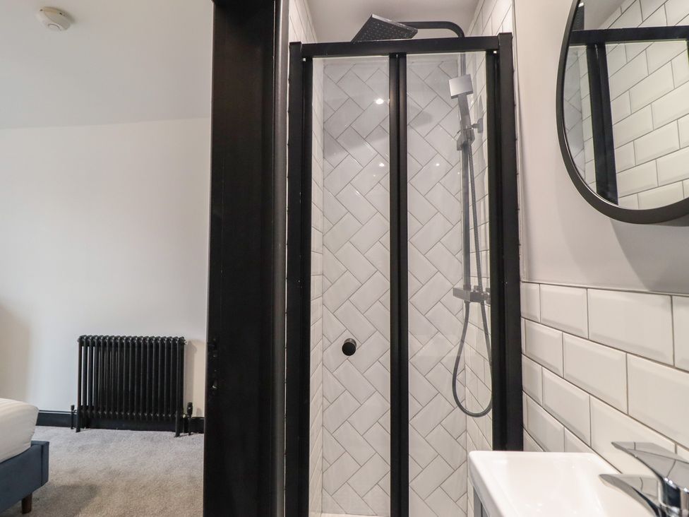 A shower with glass enclosure and sink at Green Bank in Betws-Y-Coed