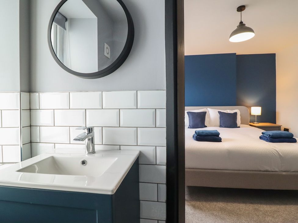 A bathroom with sink and mirror adjacent to a bedroom at Green Bank in Betws-Y-Coed