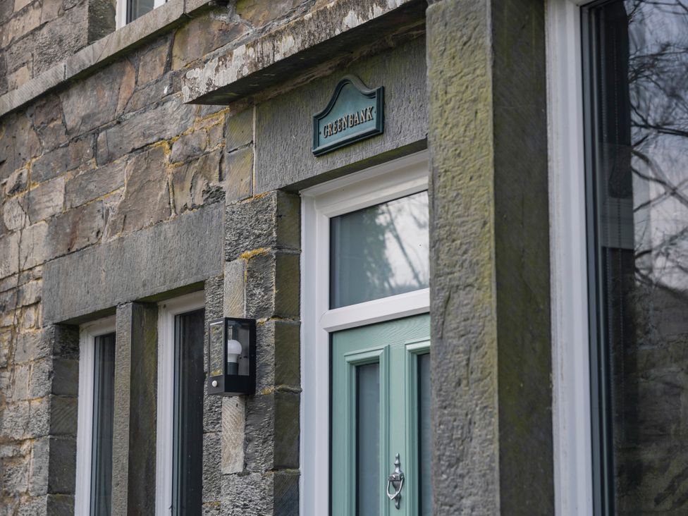 An entrance with a green door and stone wall at Green Bank in Betws-Y-Coed