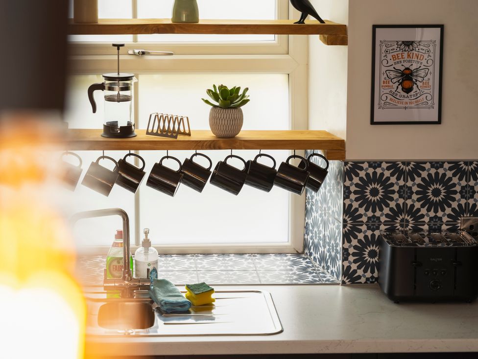 A kitchen with mugs on a shelf and a sink at Green Bank Betws-Y-Coed