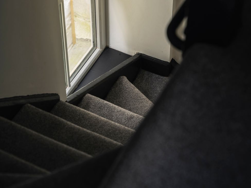 A staircase with a carpeted surface and a window at Green Bank in Betws-Y-Coed
