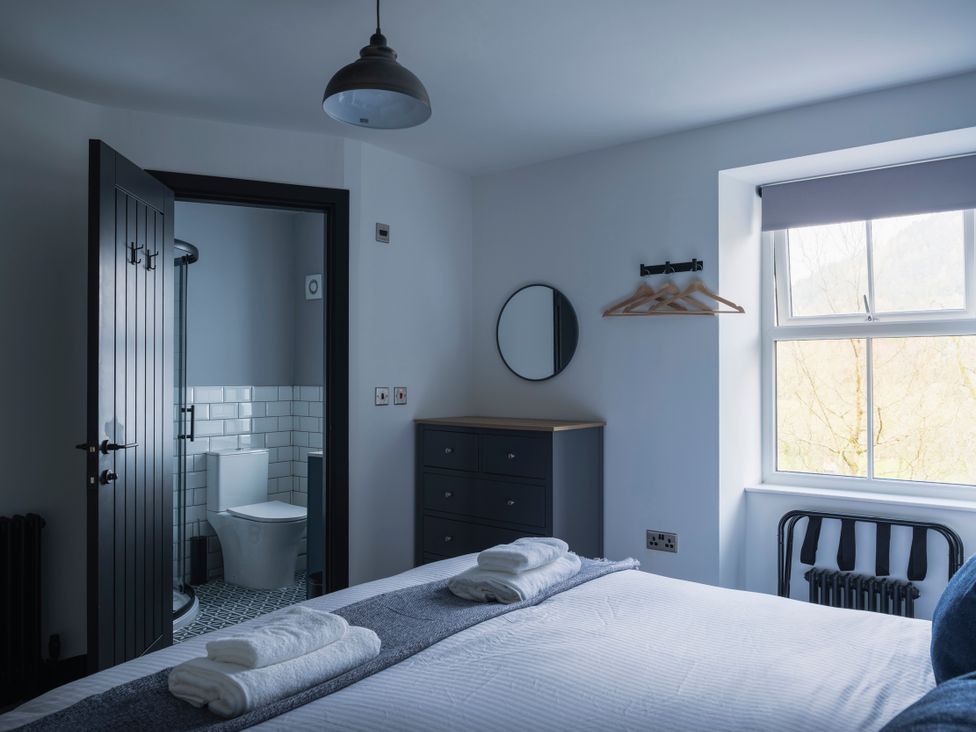 A bedroom with a bed and bathroom entrance at Green Bank in Betws-Y-Coed