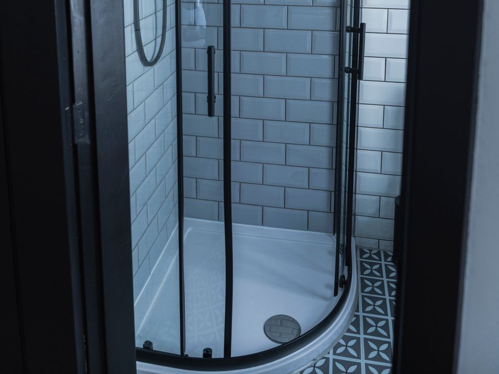 A shower with glass doors and tiled walls at Green Bank in Betws-Y-Coed