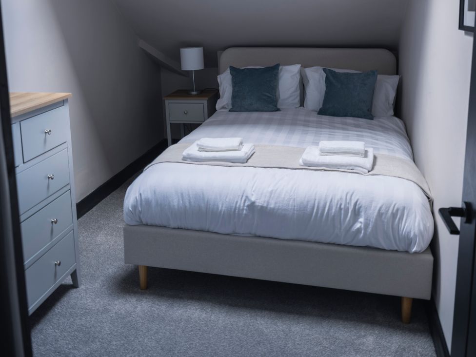 A bedroom with a bed, nightstand, dresser, and lamp at Green Bank in Betws-Y-Coed