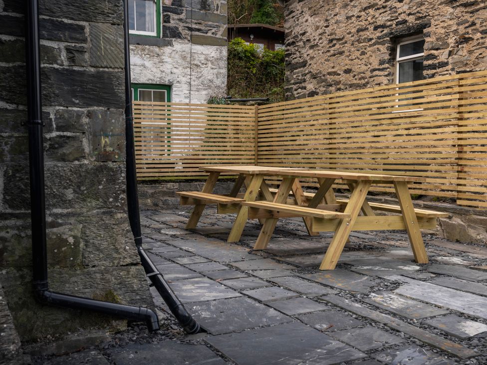 An outdoor area with wooden table and benches at Green Bank in Betws-Y-Coed