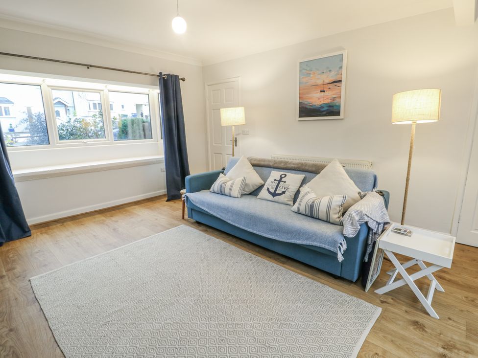 A living room with a sofa and lamp at 16 Ffordd Meigan in Beaumaris