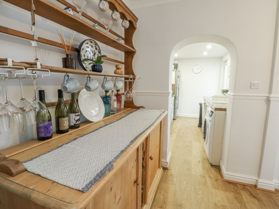 A kitchen with a wooden shelf and wine bottles at 16 Ffordd Meigan Beaumaris