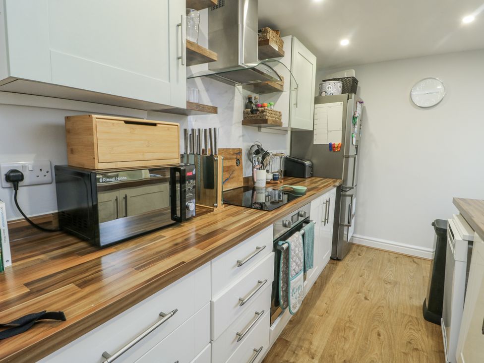 A kitchen with a microwave, fridge, and various appliances at 16 Ffordd Meigan Beaumaris