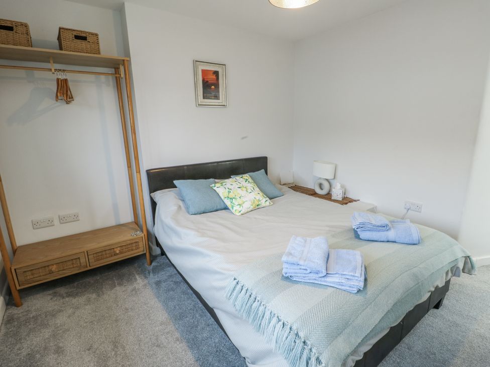 A bedroom with a bed, hanging rack and bedside table at 16 Ffordd Meigan Beaumaris