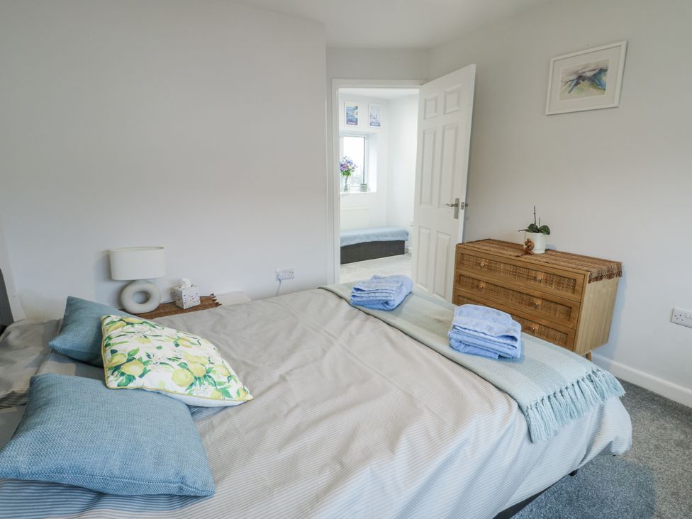 A bedroom with a bed and dresser at 16 Ffordd Meigan Beaumaris
