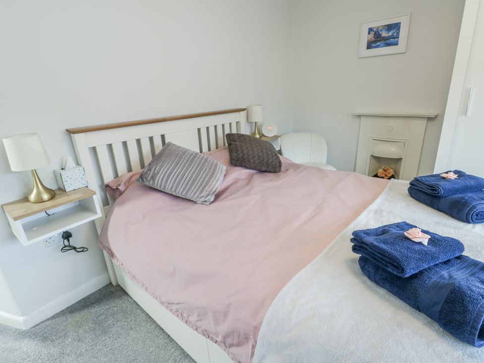 A bedroom with a bed and pillows at 16 Ffordd Meigan Beaumaris