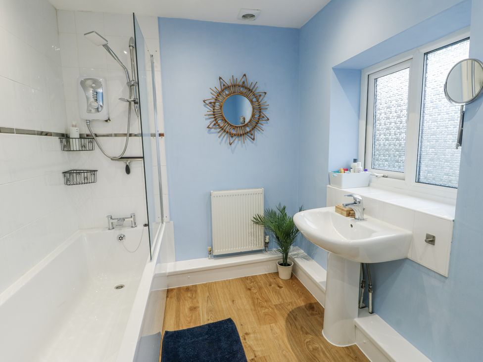 A bathroom with a bathtub and sink at 16 Ffordd Meigan Beaumaris