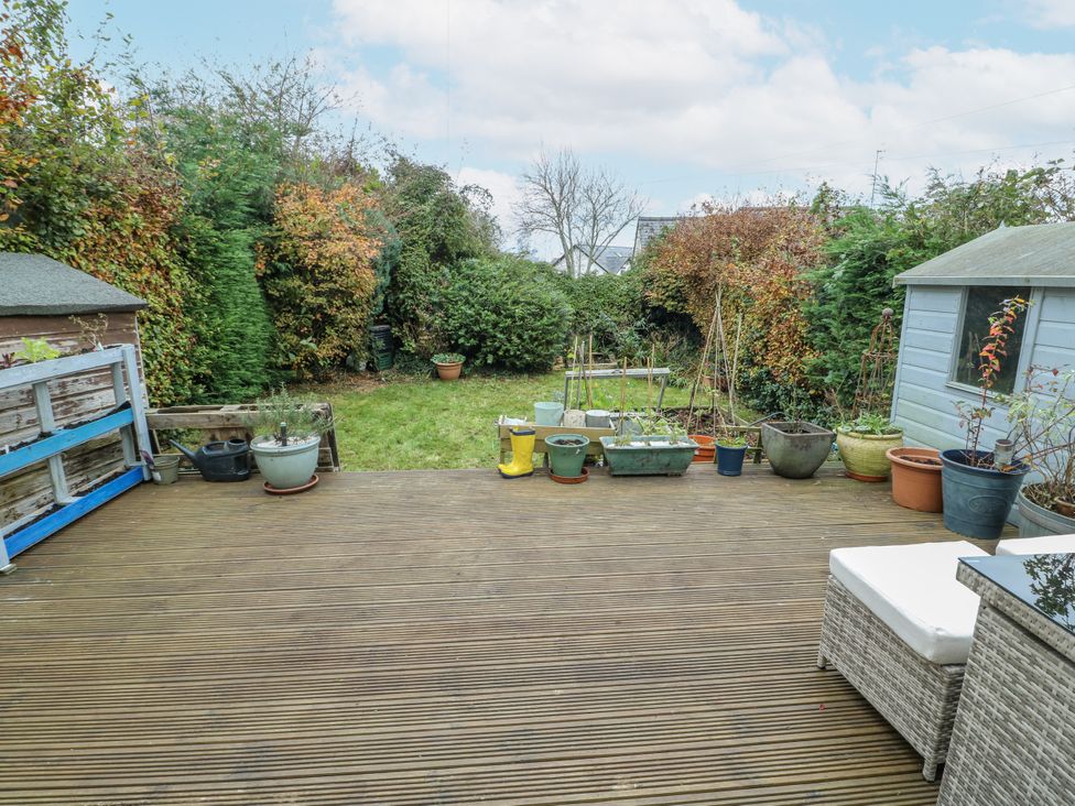 A garden with decking, planters, and a shed at 16 Ffordd Meigan Beaumaris
