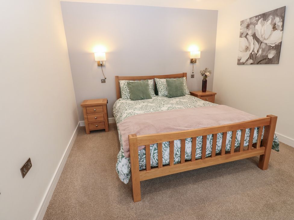 A bedroom with a bed, bedside table and lamp at Cobble Cottage in Long Marton near Appleby-In-Westmorland