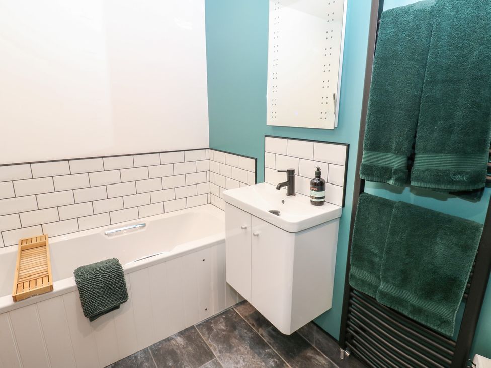 A bathroom with a bathtub, sink, and towels at Cobble Cottage, Long Marton near Appleby-In-Westmorland