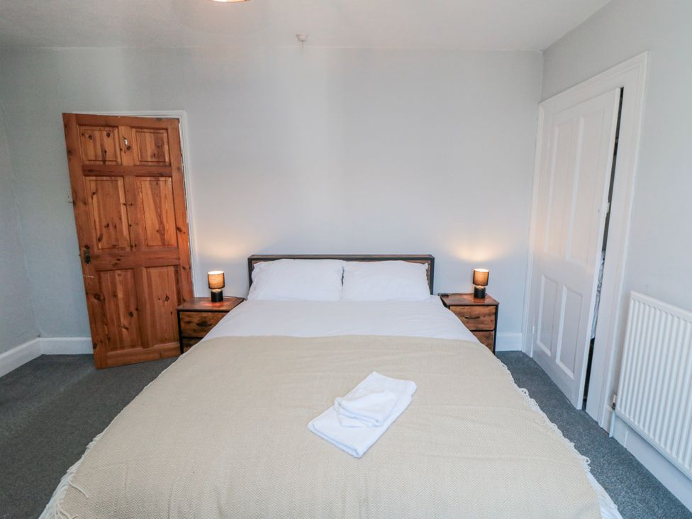 A bedroom with a bed and nightstands at Captain Jacks in Whitby