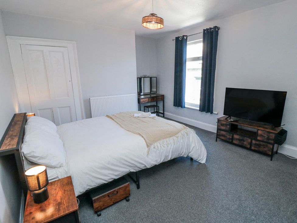 A bedroom with a bed, television, and mirror at Captain Jacks in Whitby