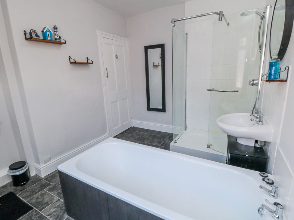 A bathroom with a bathtub, shower, and sink at Captain Jacks in Whitby