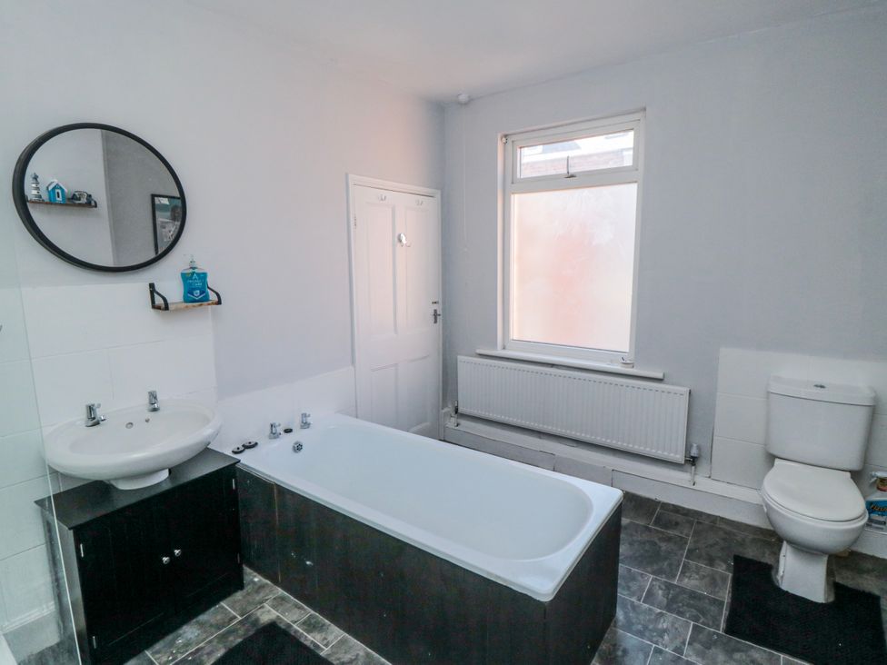 A bathroom with a bath tub, sink, and toilet at Captain Jacks in Whitby
