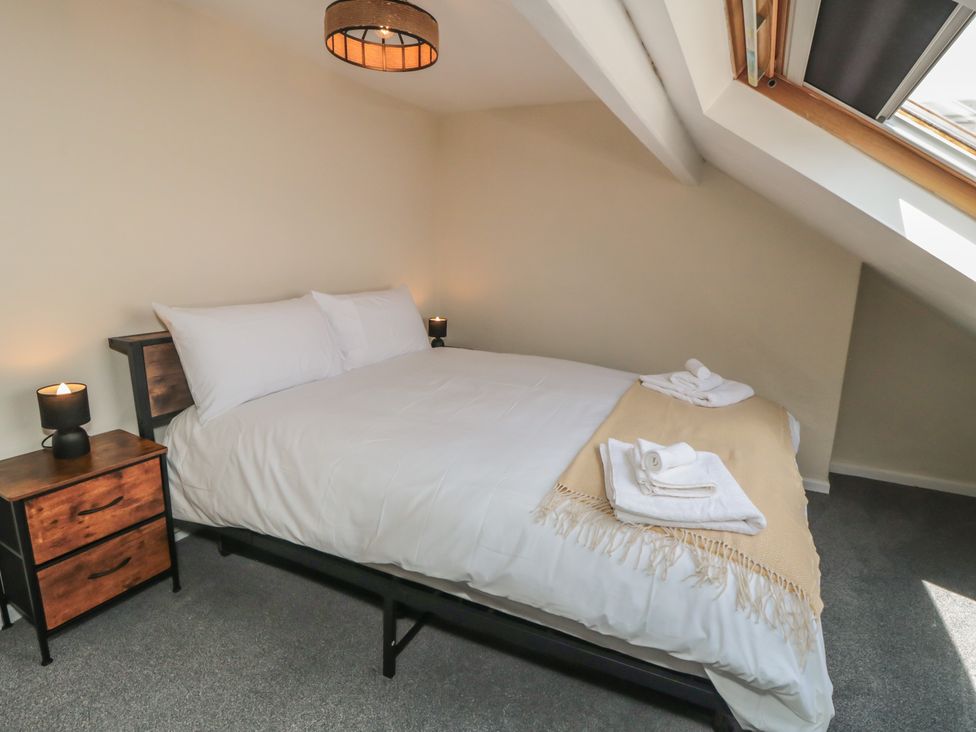 A bedroom with a bed, nightstand, and window at Captain Jacks in Whitby