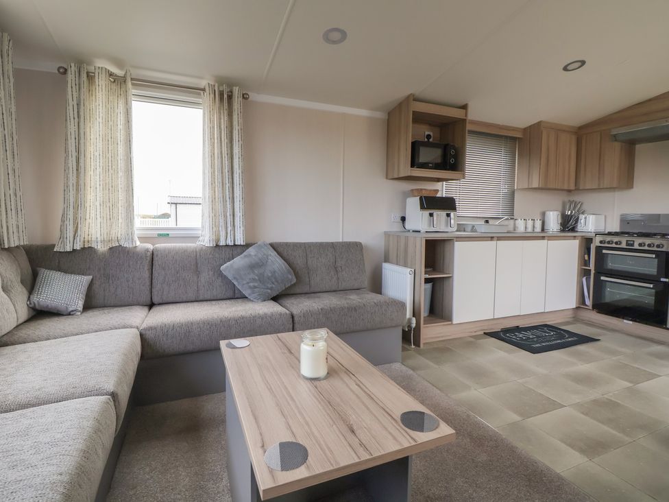 A living room with a sofa and kitchen area at MC15 in Rhyl