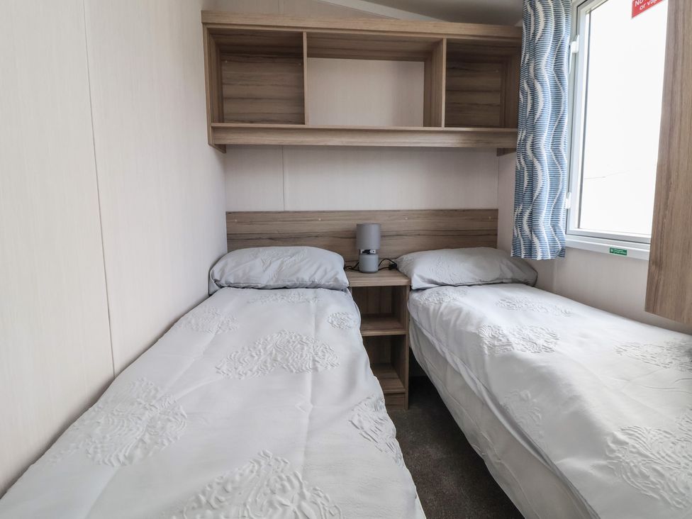 A bedroom with two beds and a nightstand at MC15 in Rhyl