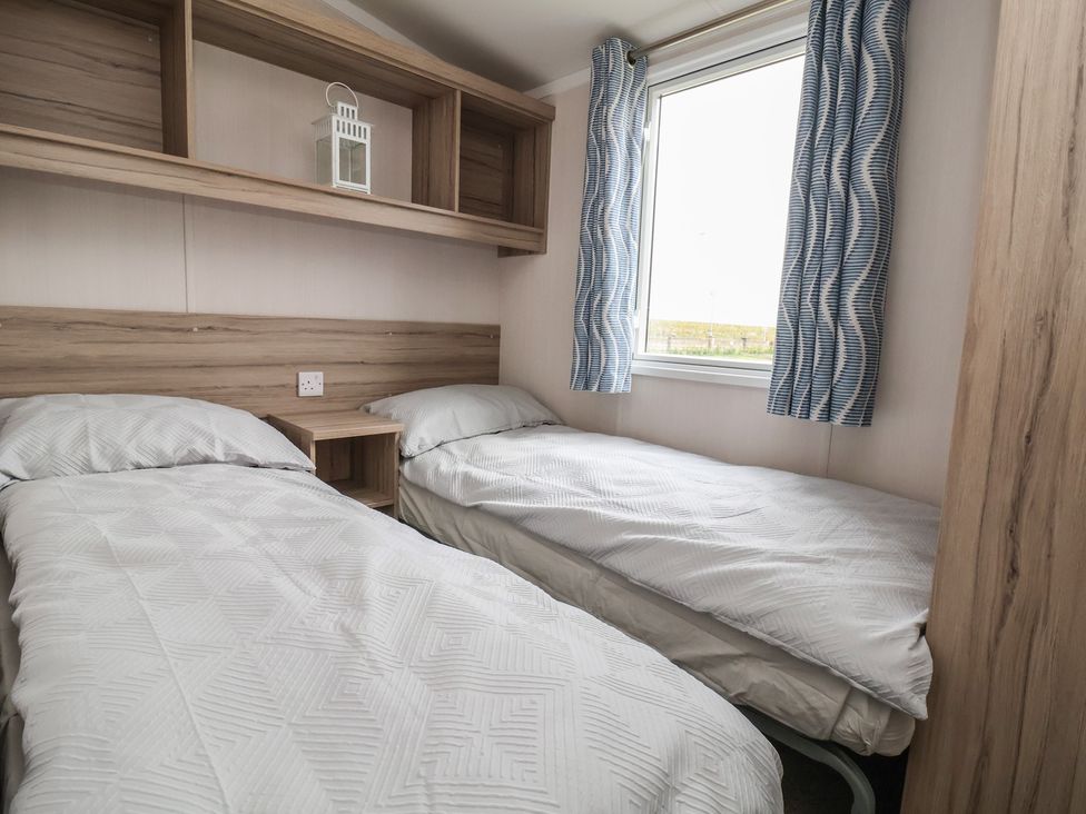 A bedroom with two single beds and a window at MC15 in Rhyl