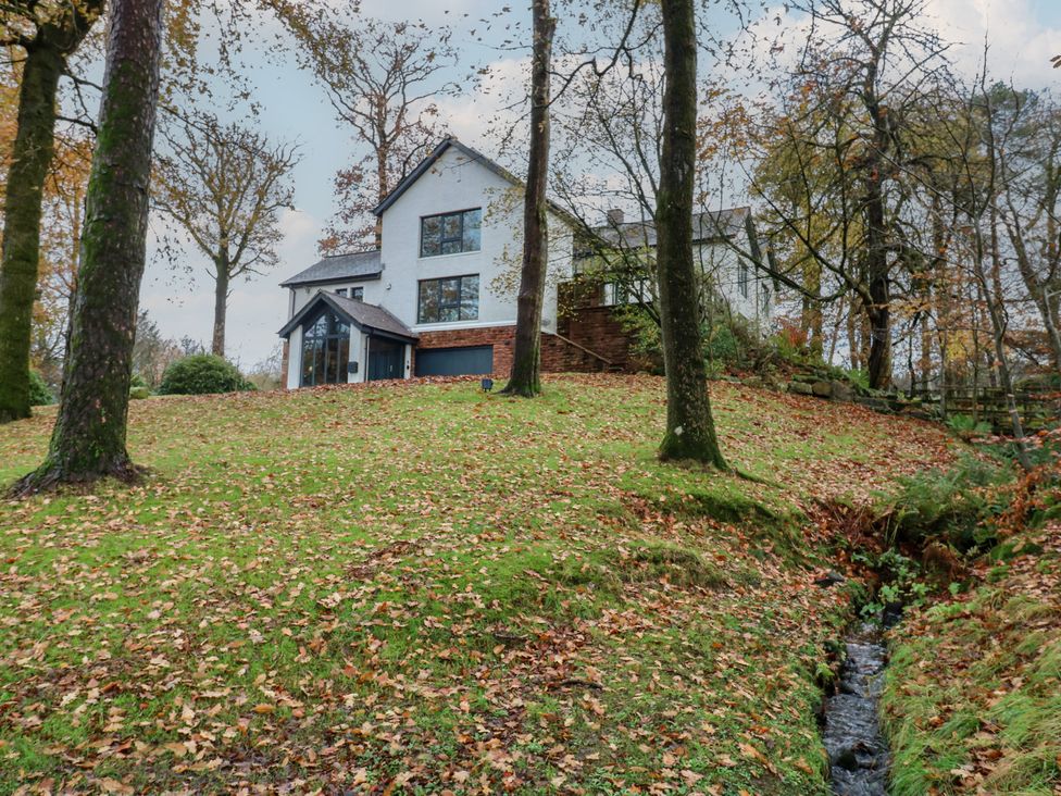 A house on a hillside surrounded by trees and a stream at Chapel Hill in Catlowdy