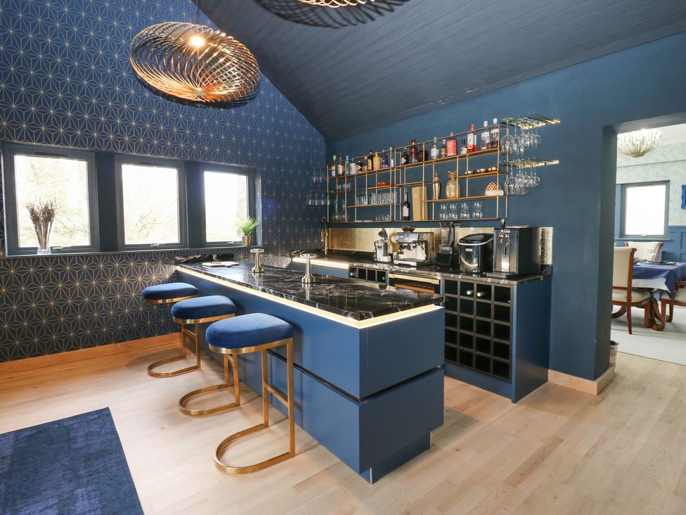 A kitchen with a blue island and bar stools at Chapel Hill in Catlowdy