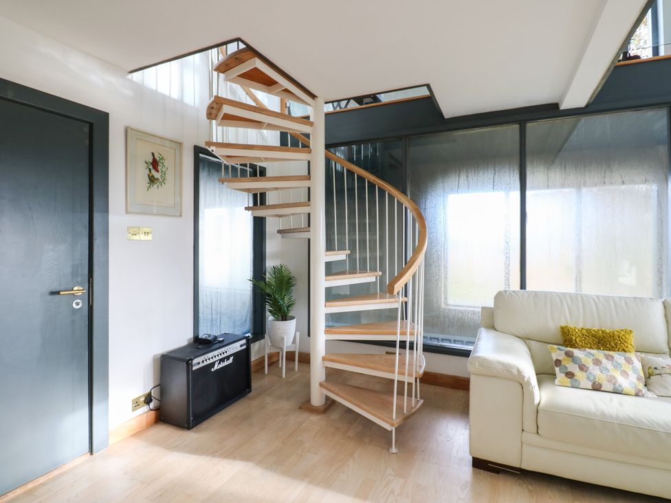 A living room with a spiral staircase and a sofa at Chapel Hill in Catlowdy