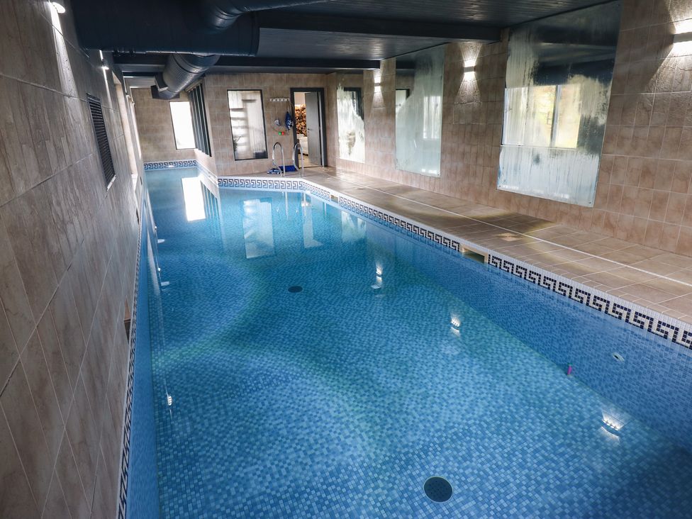 A swimming pool with tiled walls and mirrors at Chapel Hill in Catlowdy