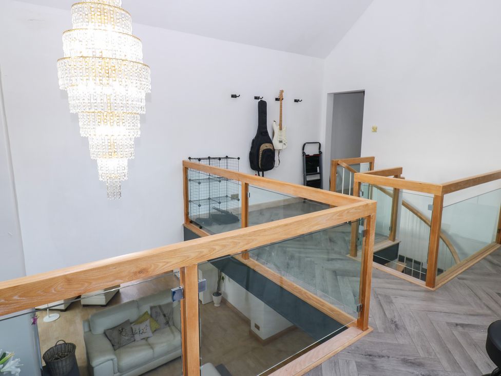 A living room with a chandelier and guitars on the wall at Chapel Hill in Catlowdy