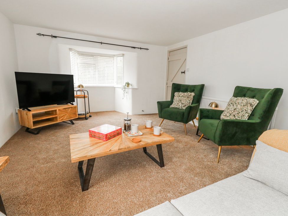 A living room with green armchairs and a coffee table at Long Barn in Burton Bradstock