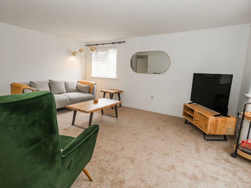 A living room with a sofa, armchair, coffee table, and television at Long Barn in Burton Bradstock