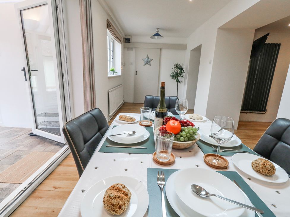 A dining room with a table set for a meal featuring fruit and wine at Long Barn in Burton Bradstock