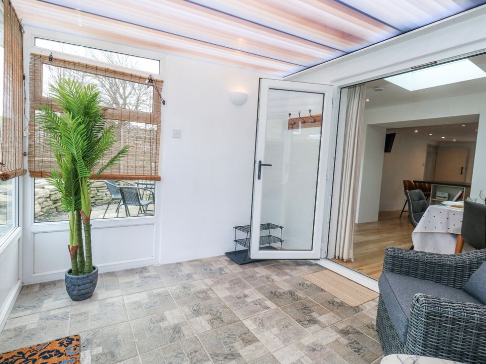 A conservatory with a plant and seating area at Long Barn in Burton Bradstock