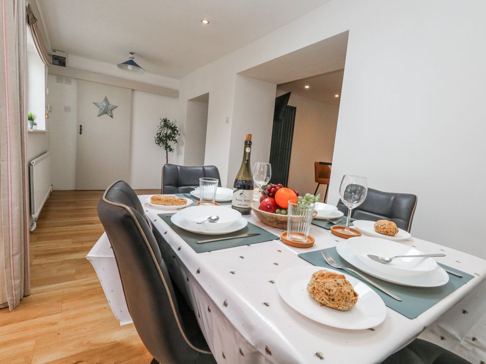 A dining room with a table set for meals at Long Barn in Burton Bradstock